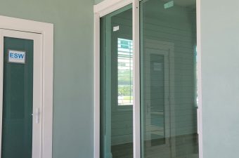Glass sliding door with a green wall and window reflection.