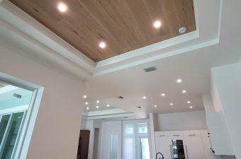 Modern ceiling with wood paneling and recessed lighting in a spacious room.