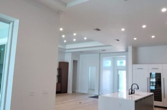 Spacious modern kitchen with white cabinetry and wooden floors.