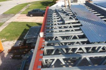 Worker on roof near solar panel installation equipment.