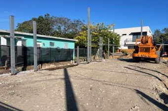 Construction site with concrete pillars and machinery under a clear sky.