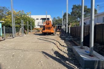 Construction site with machinery and concrete pillars under clear sky.