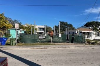 Construction site with fencing and equipment under a clear blue sky.