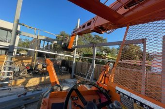 View from inside a construction vehicle showing controls and a crane arm.