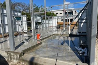 Construction site with concrete foundation and metal framework under a blue sky.