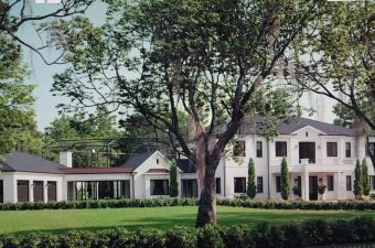 Large white mansion surrounded by lush greenery and a big tree.