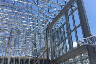 Steel framework of a building under construction with clear skies.