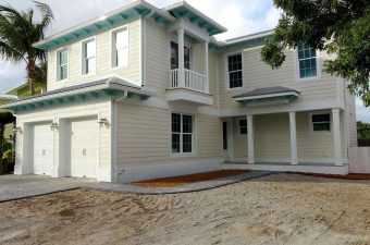 Newly constructed two-story house with beige siding and a spacious driveway.
