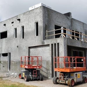 An unfinished concrete building under construction with construction lifts outside.