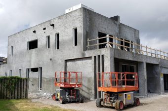 An unfinished concrete building under construction with construction lifts outside.