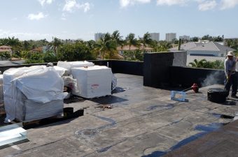 A rooftop with construction materials and equipment under a partly cloudy sky.