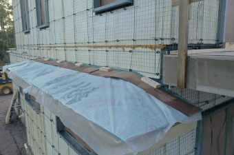 Construction site wall with insulation and protective plastic covering.