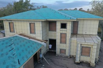 A two-story house under construction with a blue roof.