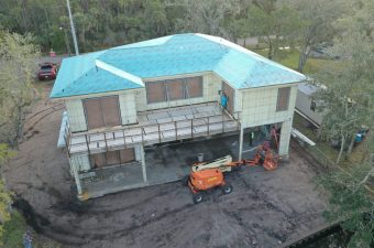 A building under construction with a blue roof and construction equipment outside.
