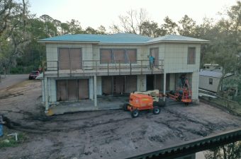 A two-story house under renovation with construction equipment outside.