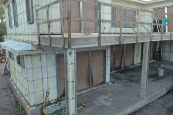 A building facade under construction with scaffolding and boarded windows.
