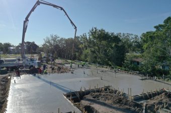 Workers pouring concrete at a construction site on a sunny day.