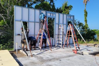 Workers installing large glass panels on a building frame outdoors.