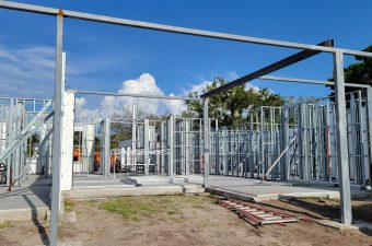 Steel frame structure under construction with clear sky.