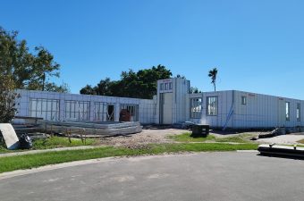 A house under construction with framed walls on a sunny day.