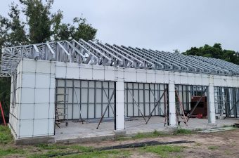 Construction of a building with exposed steel framework and concrete walls.