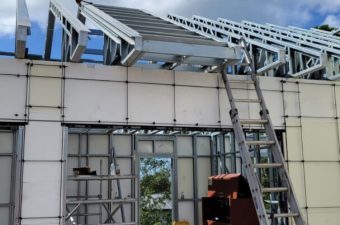 Building under construction with solar panels being installed on the roof.