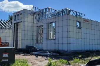 Partially built house with insulated concrete form walls and roof trusses under a blue sky.