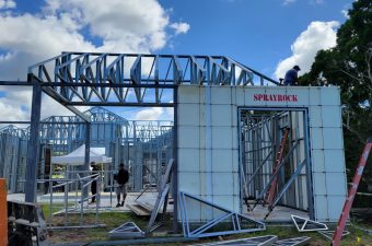 Steel framework of a building under construction with a blue sky.