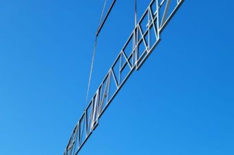 A metal ladder hanging against a clear blue sky.