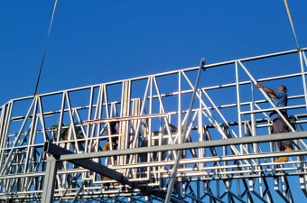 Steel framework of a billboard under construction against a clear blue sky.