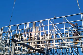 Steel framework of a billboard under construction against a clear blue sky.