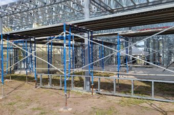 Metal scaffolding set up at a construction site under a bridge structure.