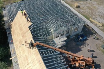 Construction workers installing roof trusses on a building under construction.