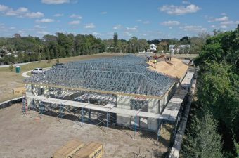 Construction site of a large building with a metal framework under a clear sky.
