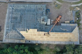 Aerial view of a large wooden roof under construction with machinery on site.