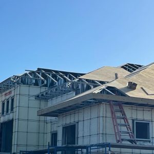 A residential building under construction with roofing work in progress.