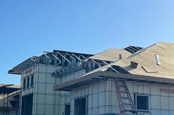 A residential building under construction with roofing work in progress.