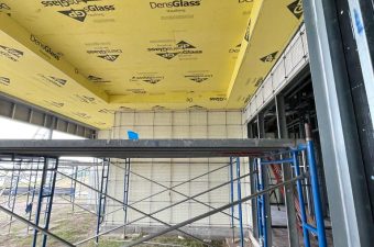 Construction site with yellow insulation panels and scaffolding.