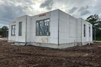 Partially built house with exposed concrete walls under a cloudy sky.