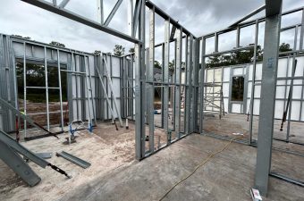 Steel framework construction for a building under cloudy skies.