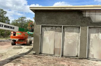 A construction site with a partially built concrete structure and a lift vehicle.