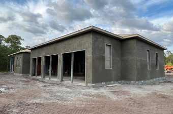 Newly constructed single-story building with unfinished exterior walls under a cloudy sky.
