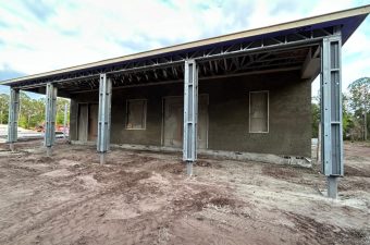 Unfinished building with exposed steel columns under a cloudy sky.