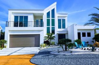 Modern white house with large glass windows and pool area.