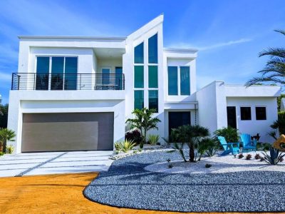Modern white house with large glass windows and pool area.