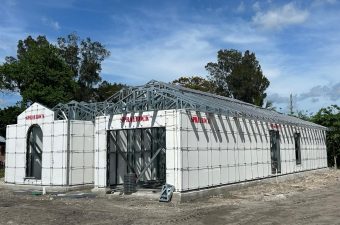 A fenced building topped with barbed wire under a partly cloudy sky.