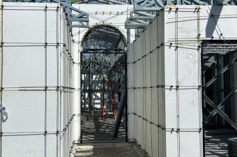 Construction site with scaffolding and protective coverings under a blue sky.