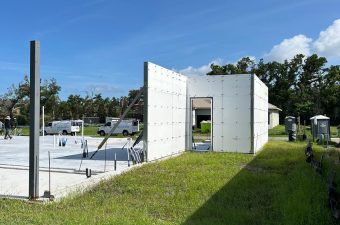 Modern architectural structure with white walls in an open grassy area.