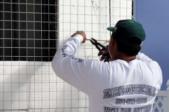 Man using a caulking gun on tiled wall.