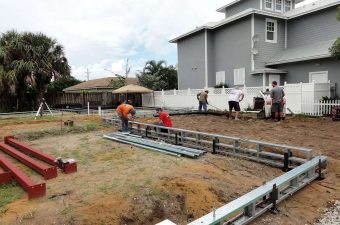 Workers preparing foundation for a new building under cloudy sky.